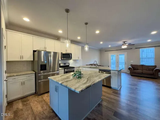 a kitchen with stainless steel appliances granite countertop a refrigerator a sink a stove a oven a sink cabinets and couches