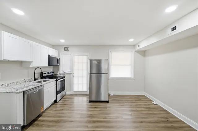 a kitchen with a sink a refrigerator and a stove top oven