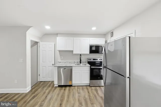 a kitchen with a refrigerator a stove top oven and white cabinets