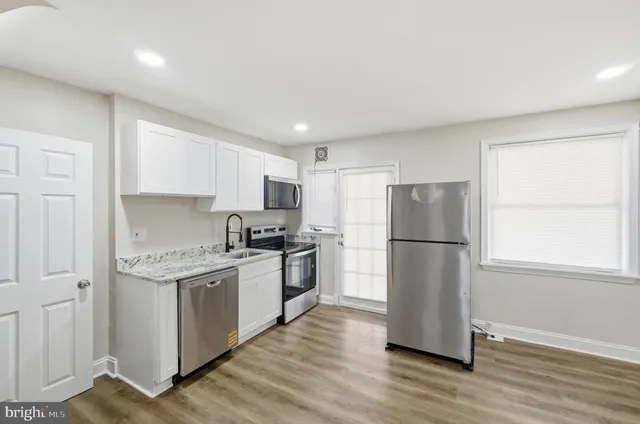 a kitchen with a refrigerator a stove top oven a sink and a window