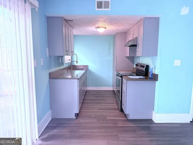 a kitchen with kitchen island granite countertop a sink cabinets and wooden floor