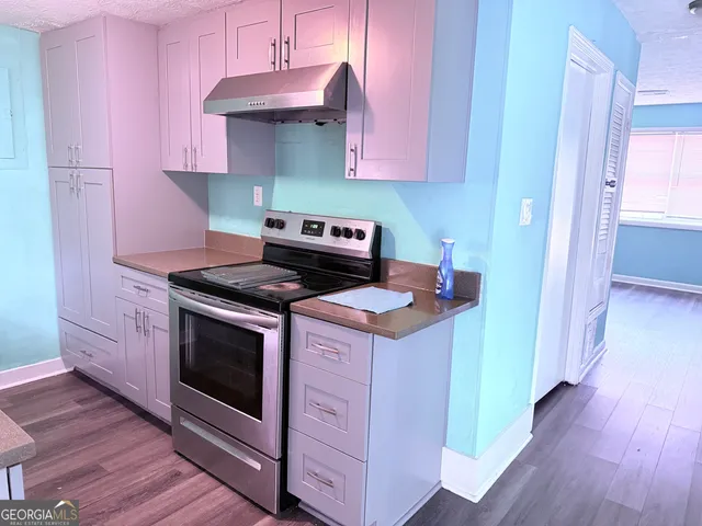 a kitchen with a stove and wooden floor