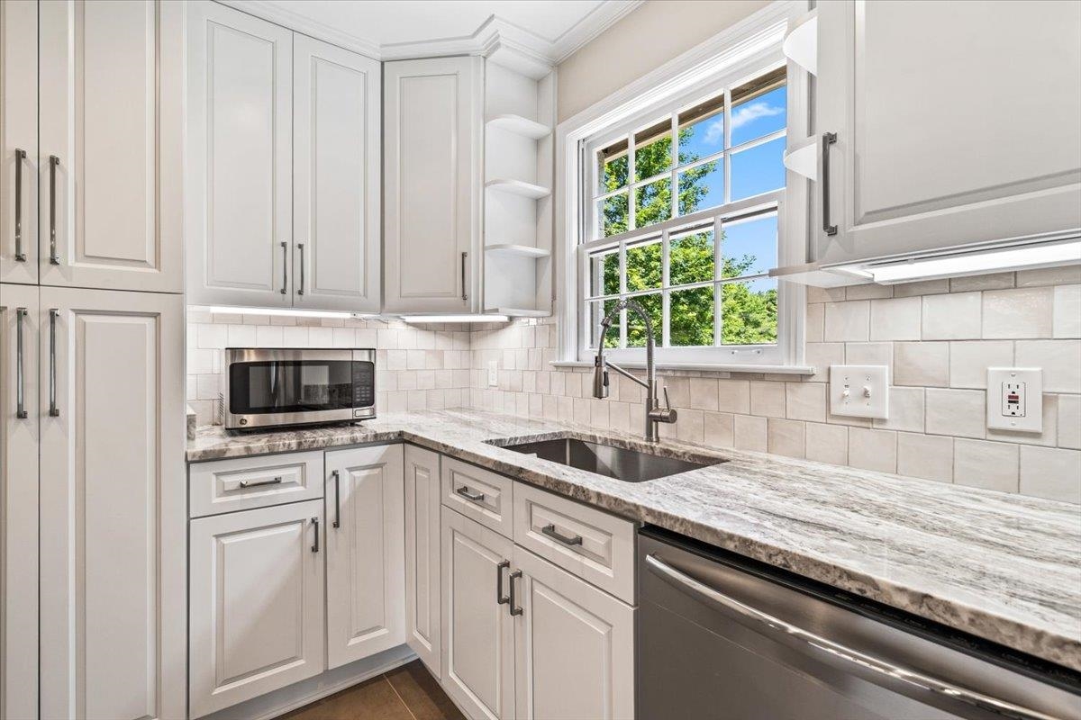 170 South Greer Street Memphis, TN 38111 - Photo 15 of 35 Kitchen featuring white shaker-style cabinetry, a stainless steel sink with a gooseneck faucet, light-toned countertops, subway tile backsplash, and under-cabinet lighting