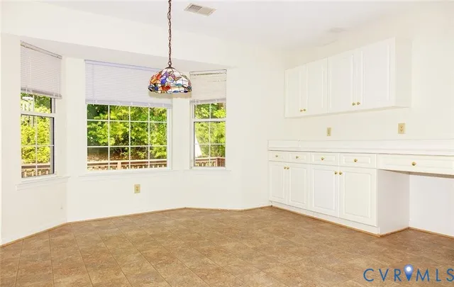 a view of a kitchen with white cabinets and window