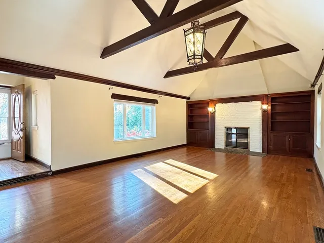 a view of an empty room with wooden floor and a window