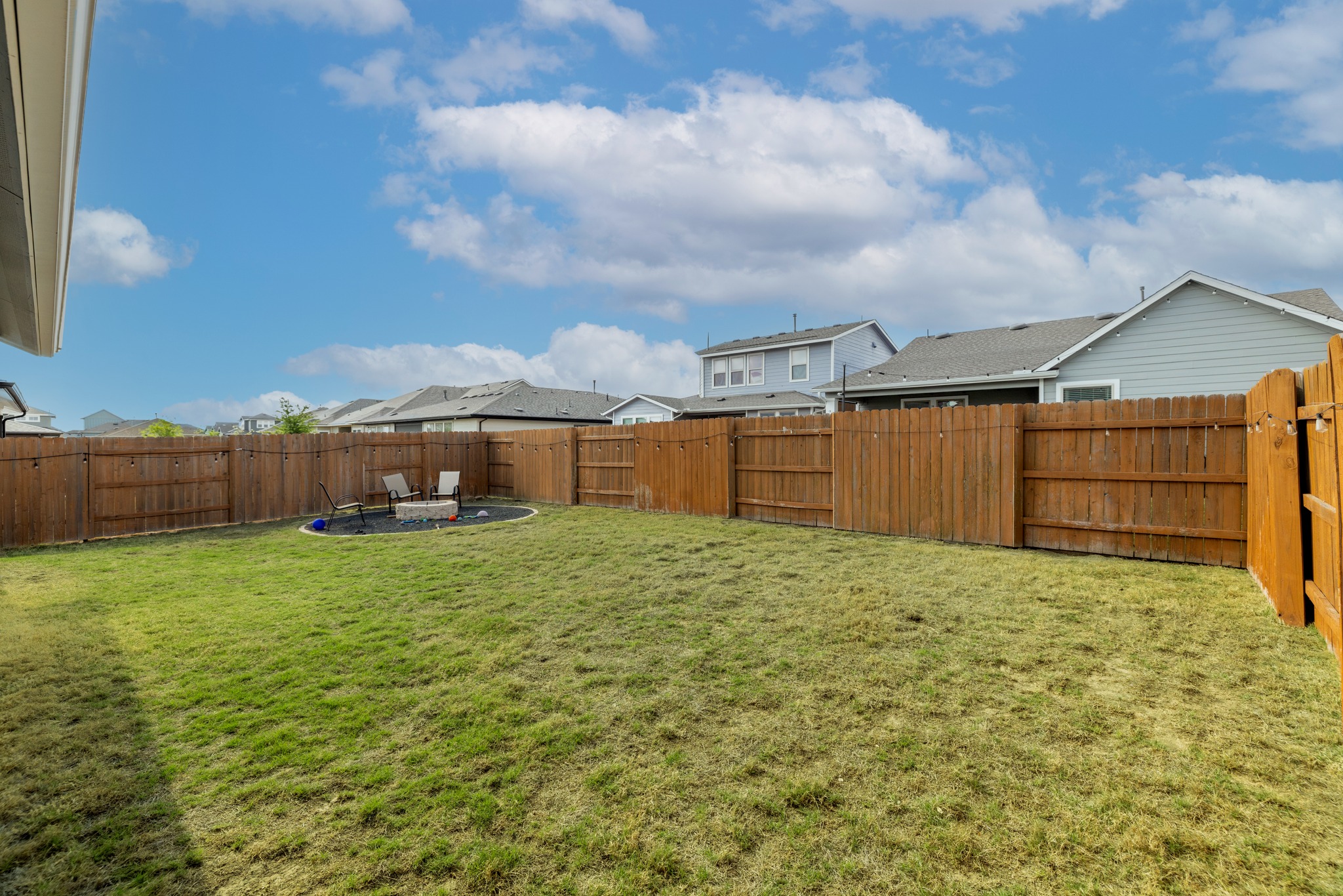 8405 Hubble Walk Austin, TX 78744 - Photo 27 of 36 Fenced backyard with a patio, a residential view, and a fire pit