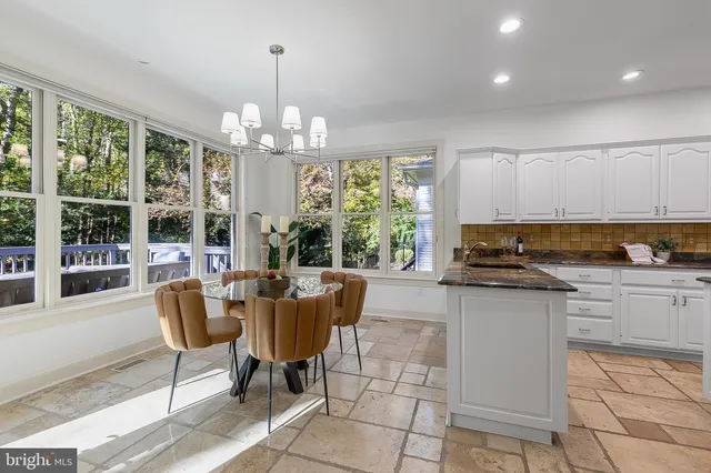 a kitchen with stainless steel appliances granite countertop a stove top oven a dining table and chairs with the chandelier