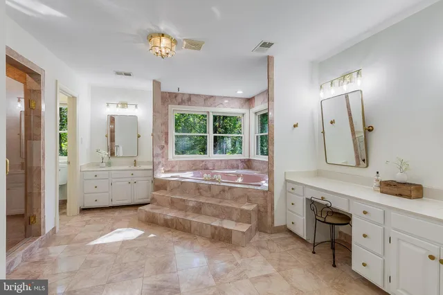 a bathroom with a tub a sink and a large mirror
