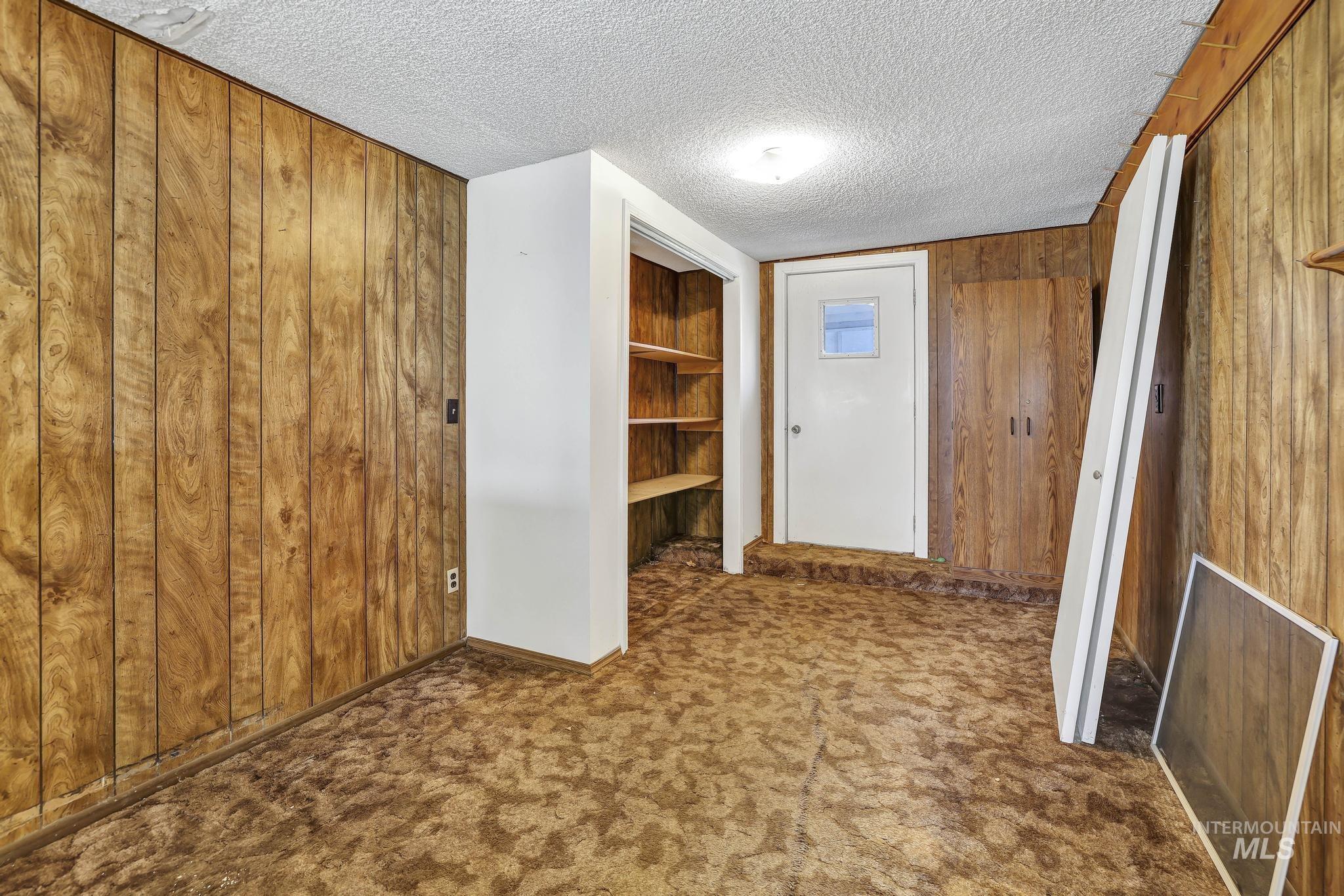 415 Adams Street Twin Falls, ID 83301 - Photo 14 of 20 Corridor featuring wood walls, a textured ceiling, and dark carpet