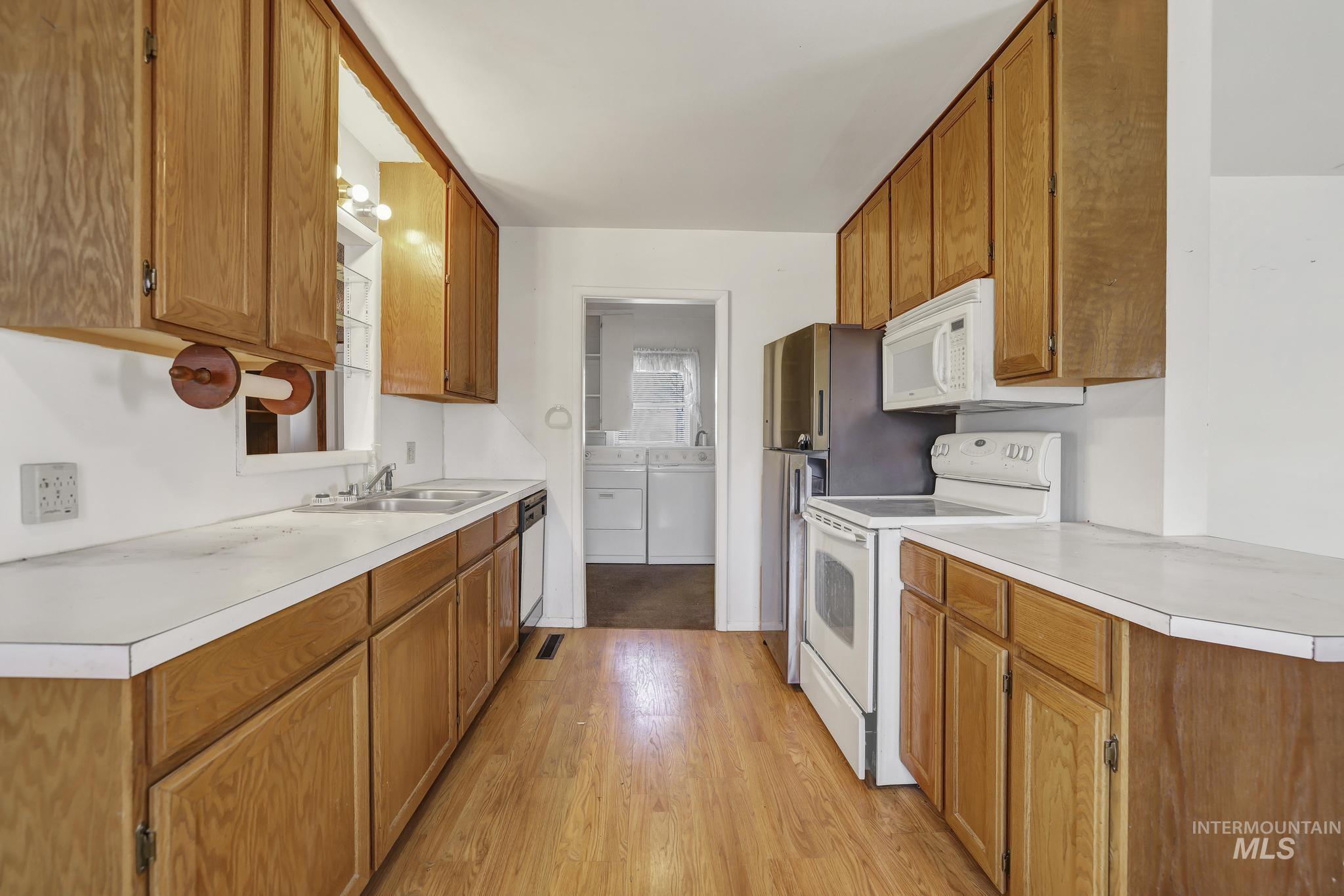 415 Adams Street Twin Falls, ID 83301 - Photo 4 of 20 Kitchen with white appliances, wood finish cabinets, light countertops, and washer and dryer