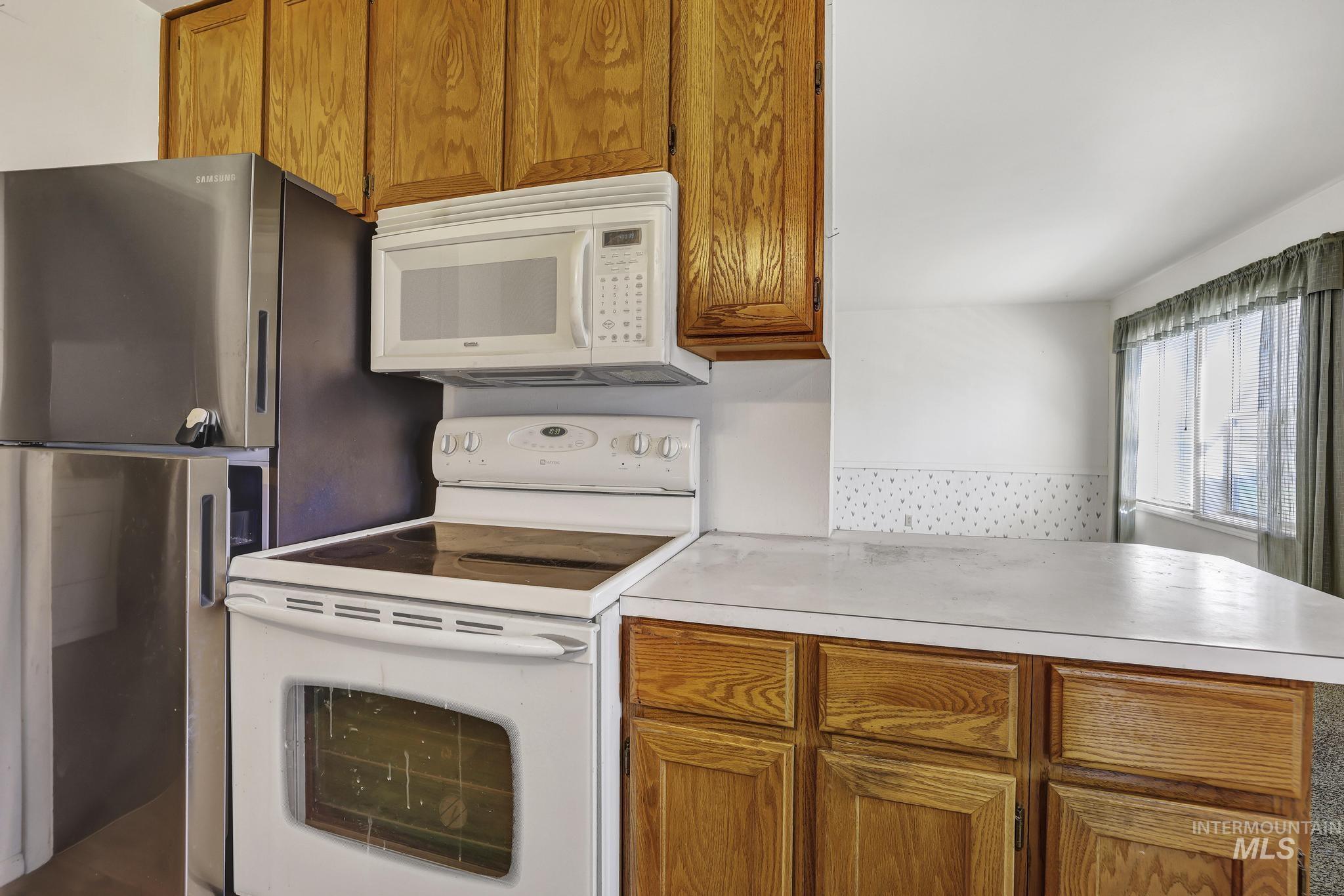415 Adams Street Twin Falls, ID 83301 - Photo 6 of 20 Kitchen with wood finish cabinets, white appliances, light countertops, and a peninsula