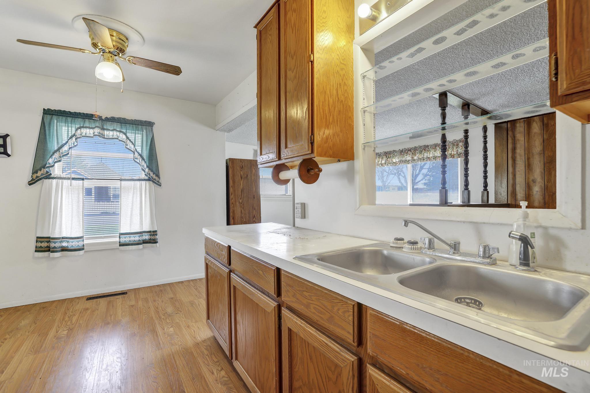 415 Adams Street Twin Falls, ID 83301 - Photo 7 of 20 Kitchen featuring wood finish cabinetry, light countertops, light wood-type flooring, and ceiling fan