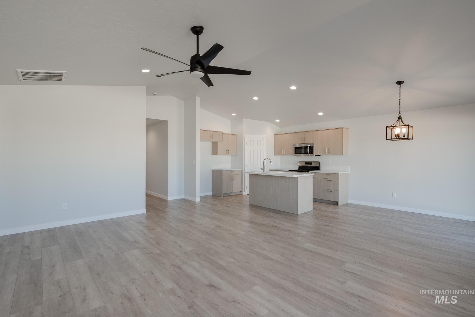 1609 Sunday River Street Middleton, ID 83644 - Photo 12 of 22 Unfurnished living room featuring light wood-style floors, vaulted ceiling, a ceiling fan, recessed lighting, and a chandelier