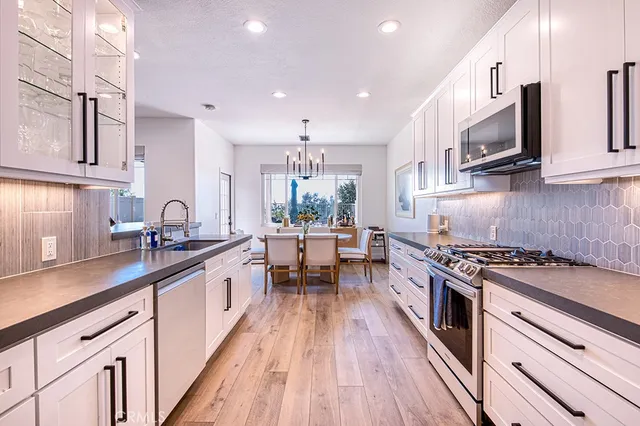 a kitchen with cabinets wooden floor and stainless steel appliances