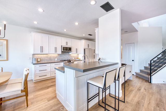 a kitchen with white cabinets stainless steel appliances and dining table