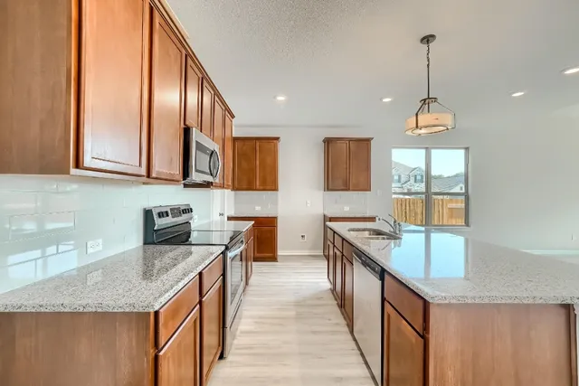 a kitchen with stainless steel appliances granite countertop hardwood floor sink stove and granite counter top