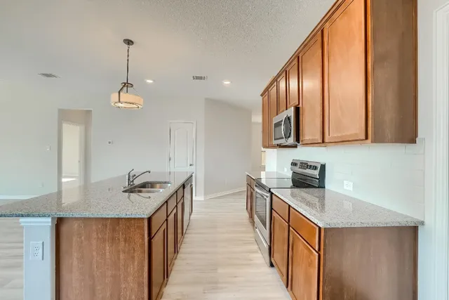 a kitchen with stainless steel appliances sink stove microwave and cabinets