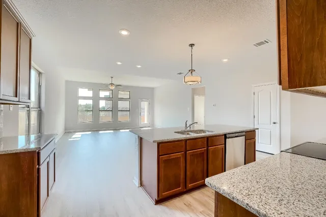a kitchen with stainless steel appliances granite countertop a sink a stove and a wooden floors