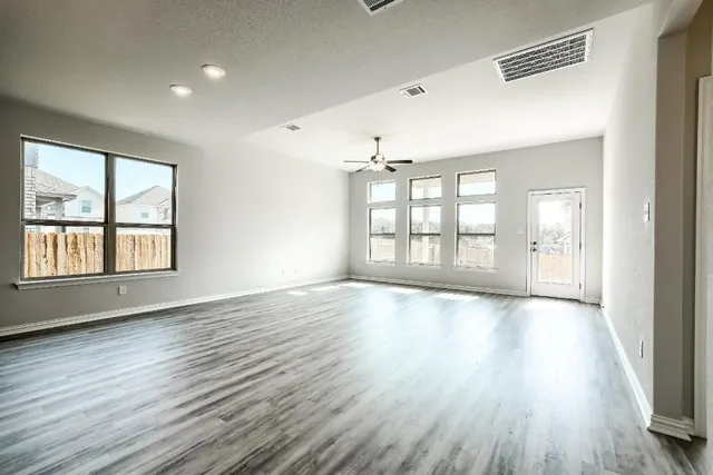 an empty room with wooden floor and windows