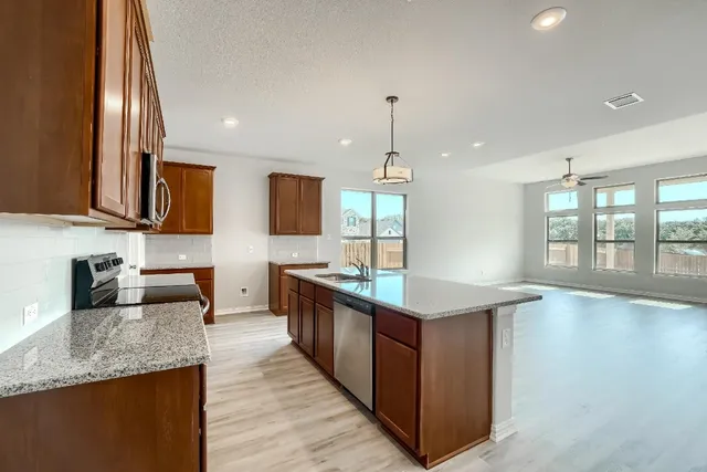 a kitchen with stainless steel appliances granite countertop a sink a stove and a wooden floors