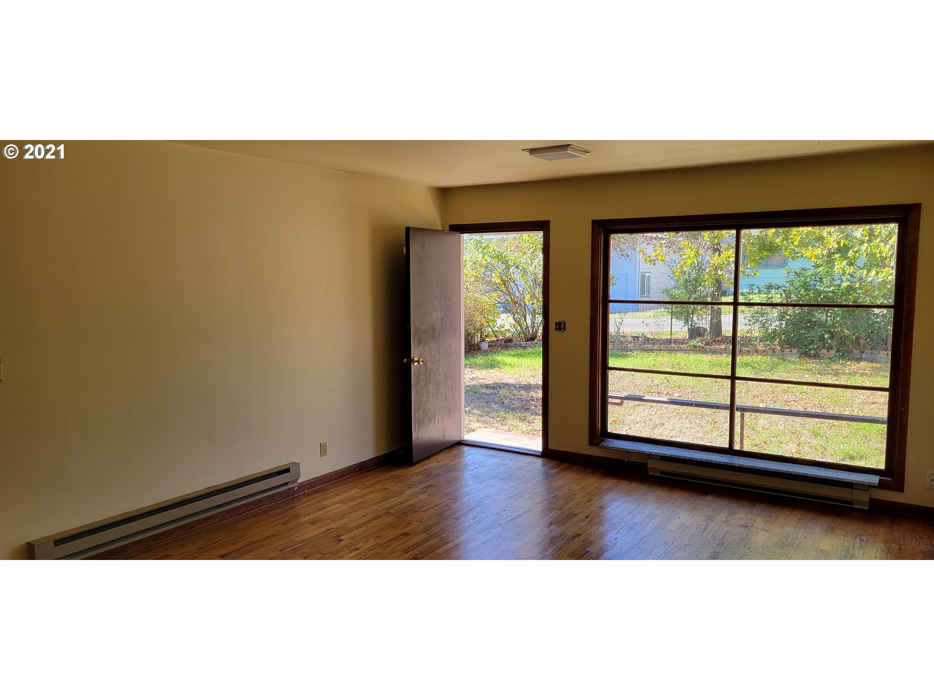 421 Smith Street Riddle, OR 97469 - Photo 3 of 14 an empty room with wooden floor and windows