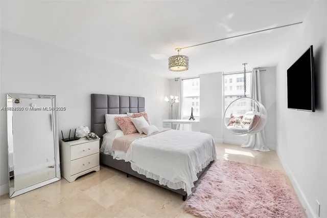 a bedroom with a bed a flat tv screen and a dresser