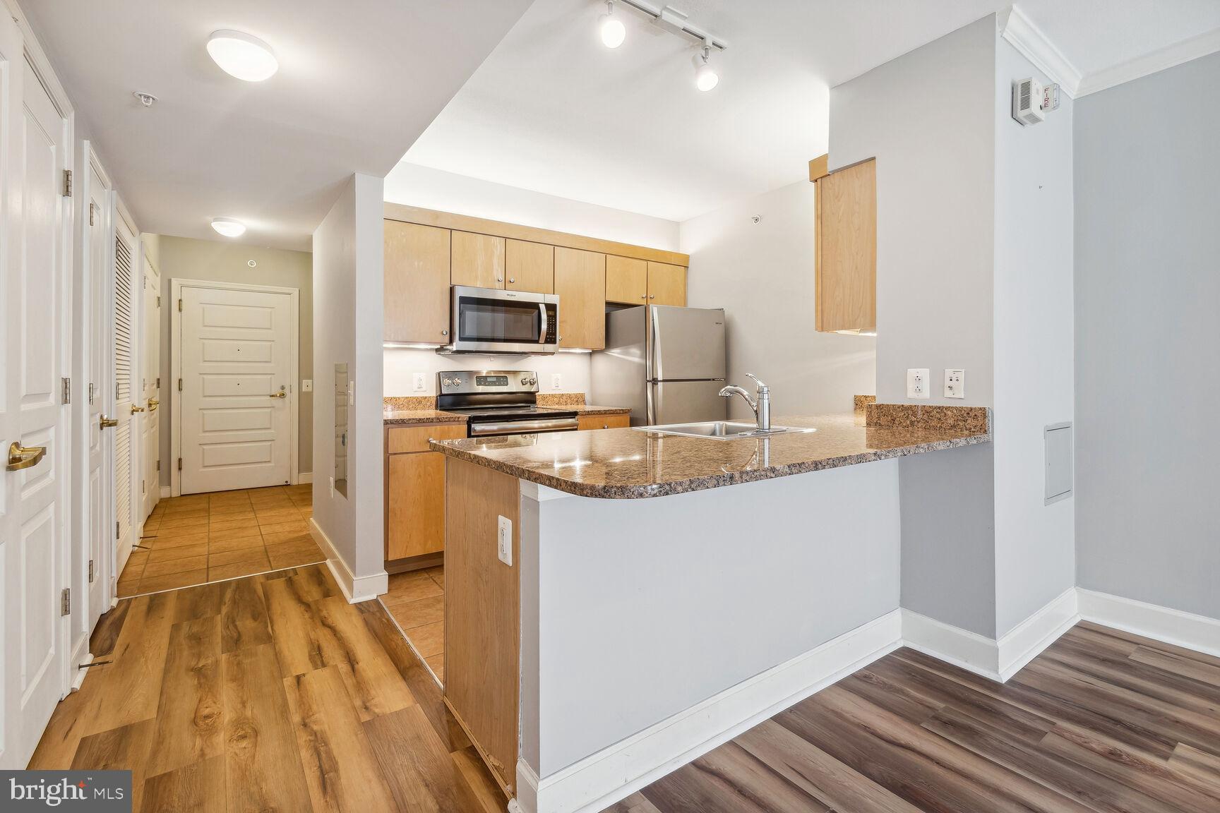 616 E Street Northwest, Unit 807 Washington, DC 20004 - Photo 6 of 24 a kitchen with kitchen island granite countertop a sink stove and refrigerator