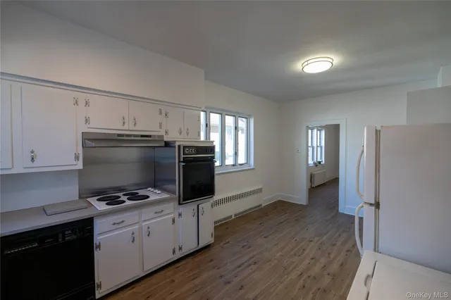 a view of a hallway with wooden floor and a bathroom