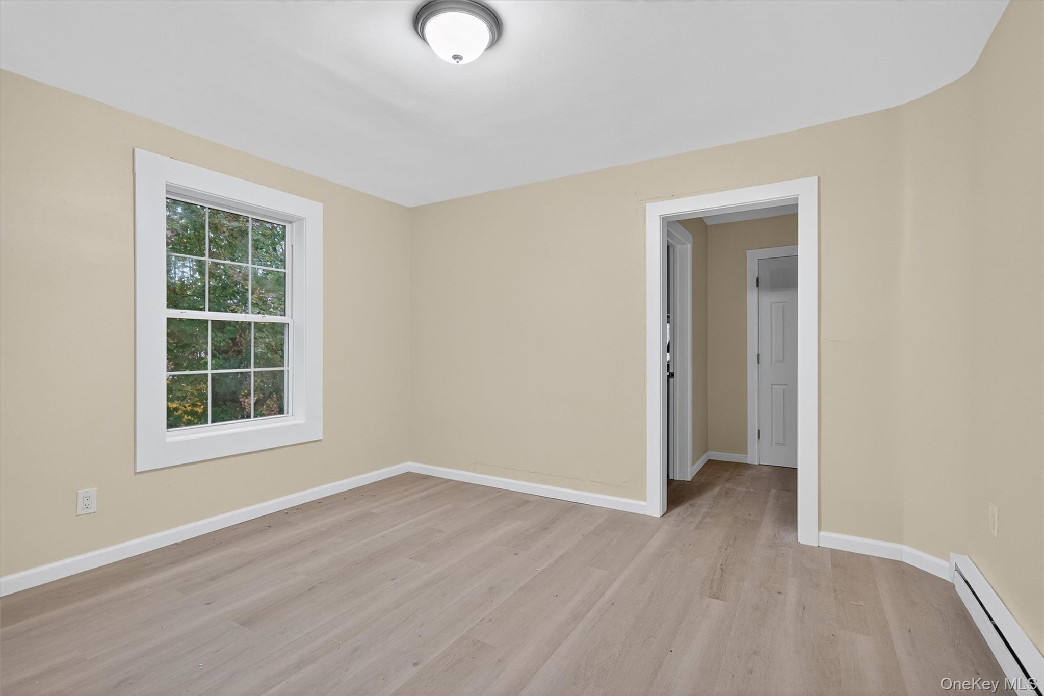 8 Cottage St Extension Monticello, NY 12701 - Photo 13 of 23 Empty room featuring a baseboard heating unit and light wood-type flooring