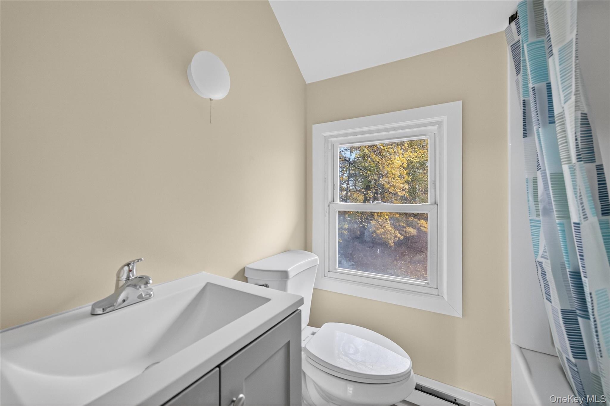 8 Cottage St Extension Monticello, NY 12701 - Photo 20 of 23 Bathroom with a heating unit, vanity, vaulted ceiling, a baseboard heating unit, and shower / tub combo with curtain