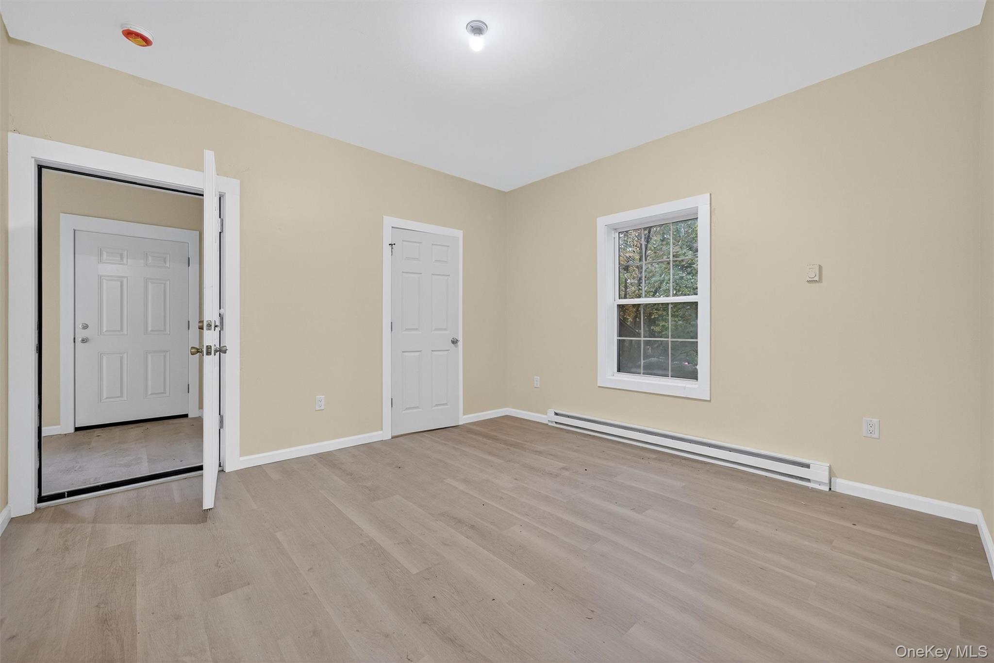 8 Cottage St Extension Monticello, NY 12701 - Photo 4 of 23 Unfurnished bedroom featuring a baseboard radiator and light wood-style flooring
