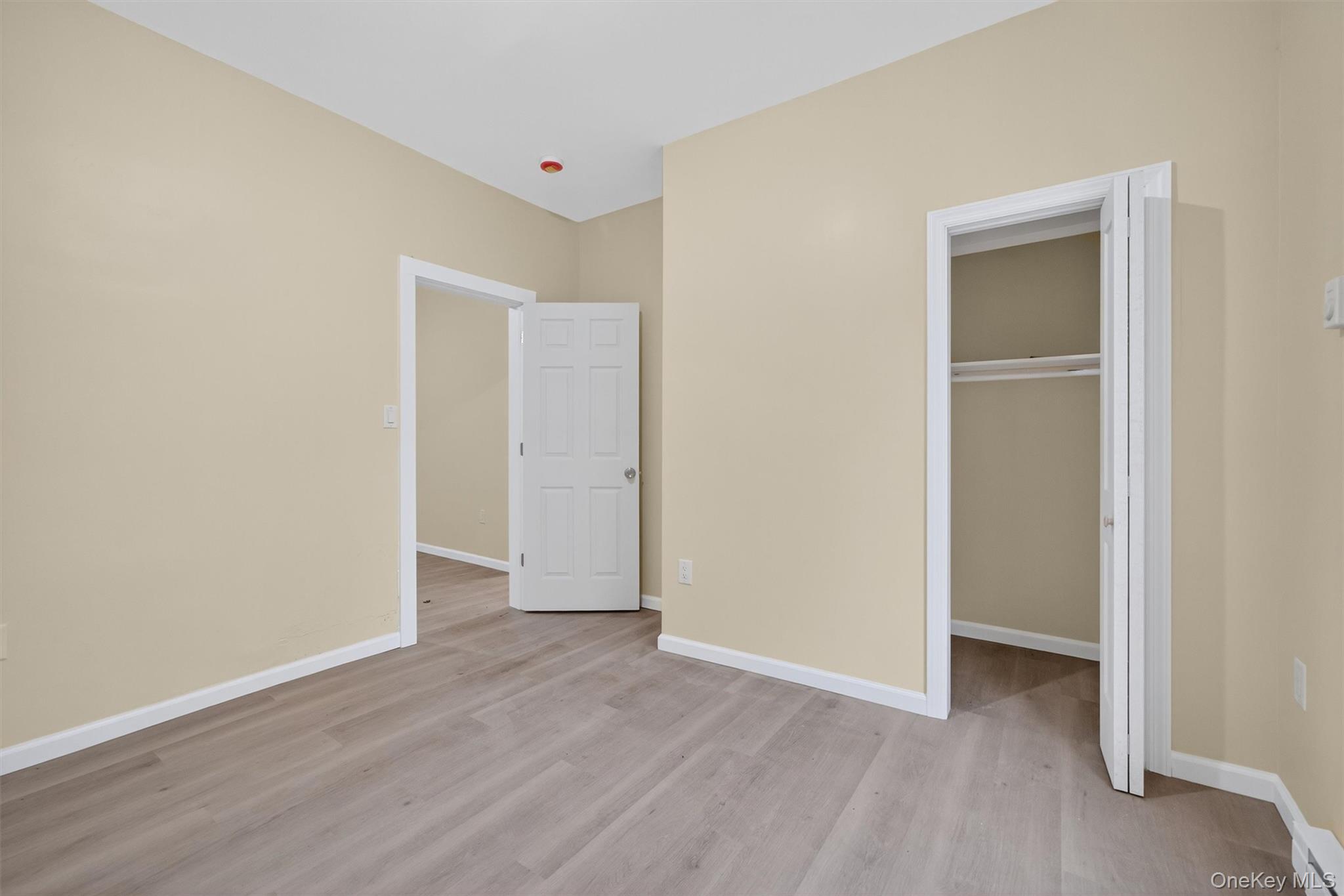 8 Cottage St Extension Monticello, NY 12701 - Photo 8 of 23 Unfurnished bedroom featuring light wood-style flooring, a walk in closet, and baseboard heating