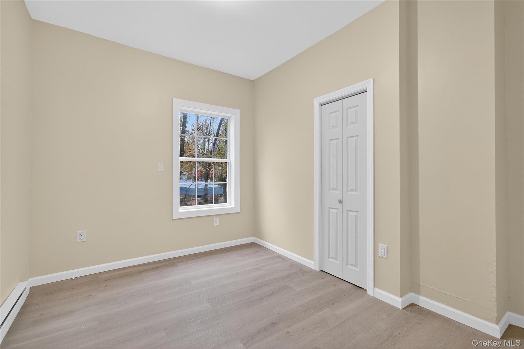 8 Cottage St Extension Monticello, NY 12701 - Photo 9 of 23 Unfurnished bedroom with light wood finished floors, a baseboard heating unit, and a closet