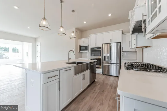 a large kitchen with stainless steel appliances a refrigerator a sink a stove a microwave a center island and wooden floor