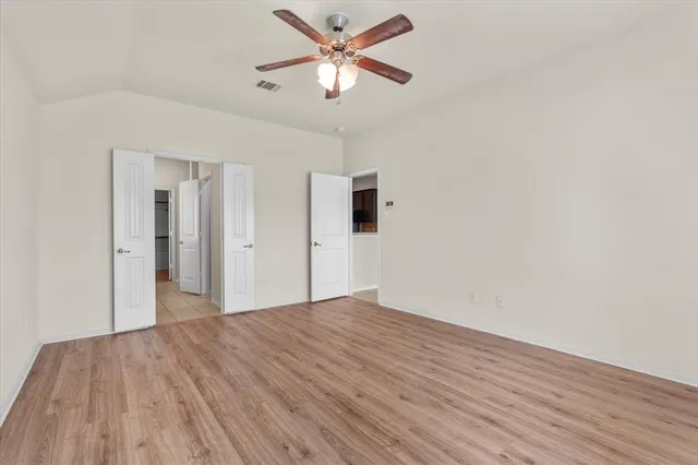 a view of a big room with wooden floor and a chandelier fan