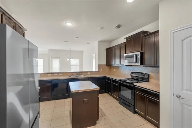 a kitchen with stainless steel appliances kitchen island granite countertop a sink and stove top oven