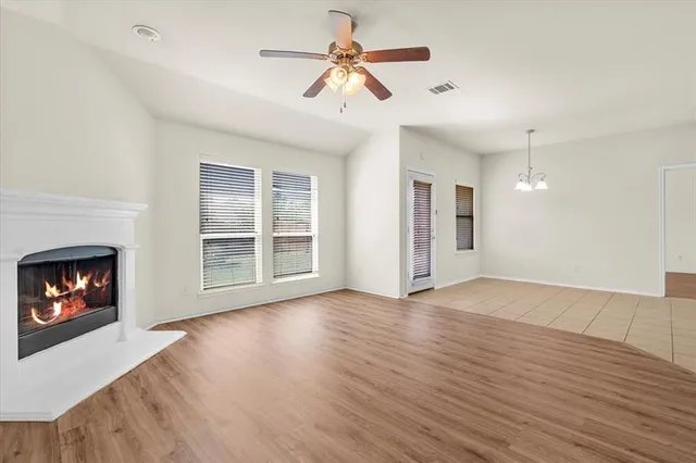 a view of an empty room with wooden floor fireplace and a window