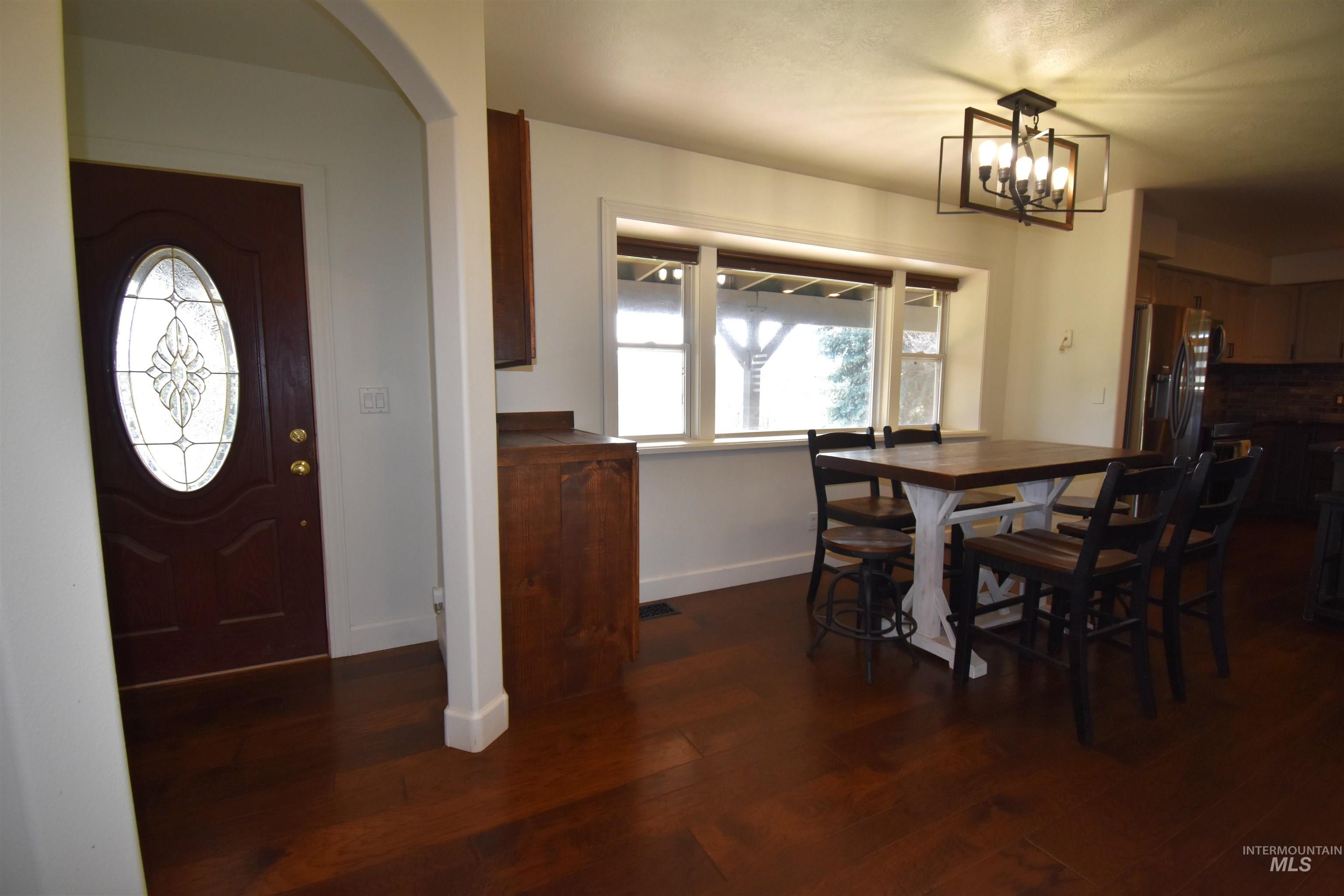 2599 Fruitvale Glendale Road Council, ID 83612 - Photo 16 of 29 Dining space with dark wood-style floors, healthy amount of natural light, arched walkways, and a chandelier