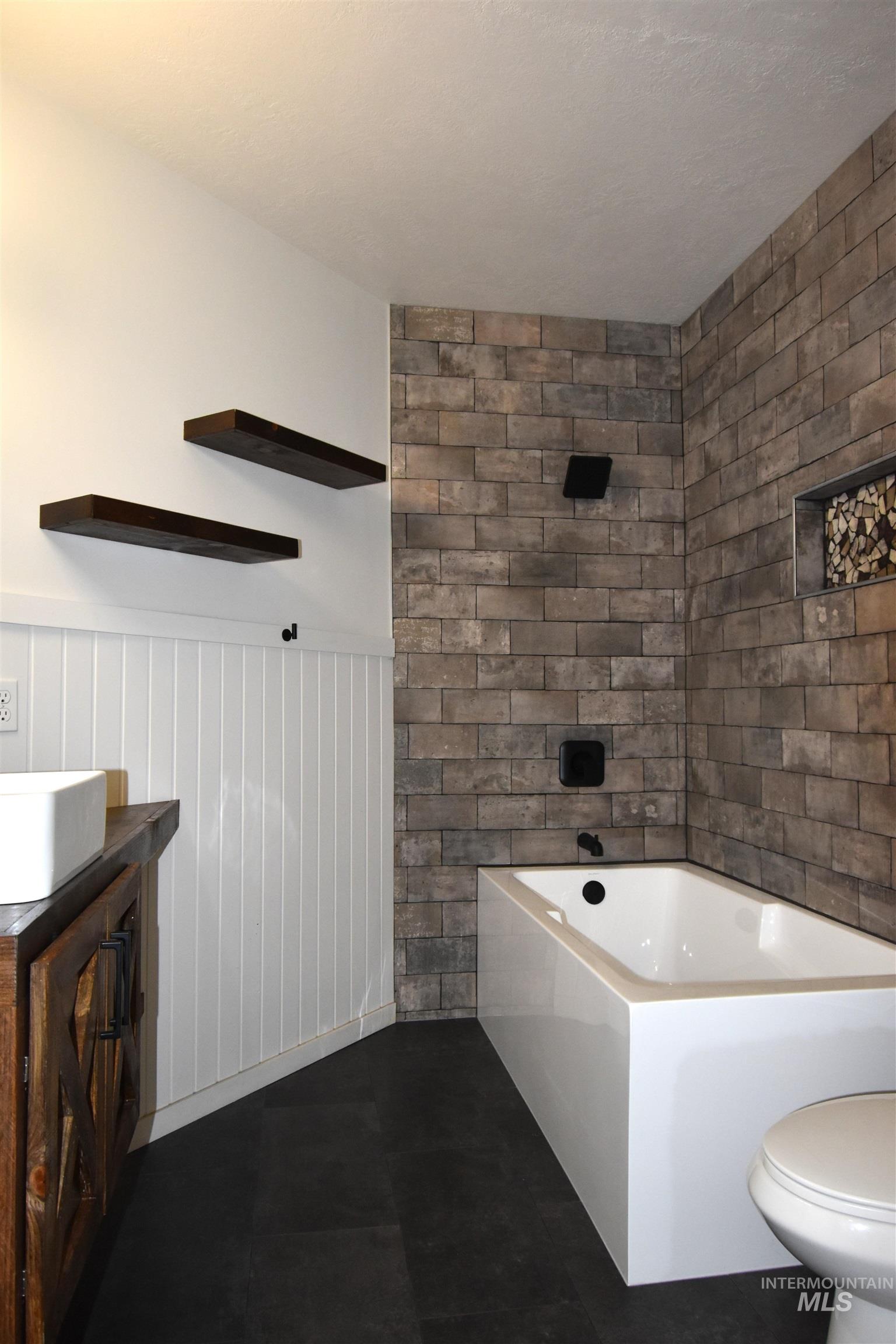 2599 Fruitvale Glendale Road Council, ID 83612 - Photo 16 of 38 Bathroom featuring vanity, a bathtub, wainscoting, and dark tile patterned flooring