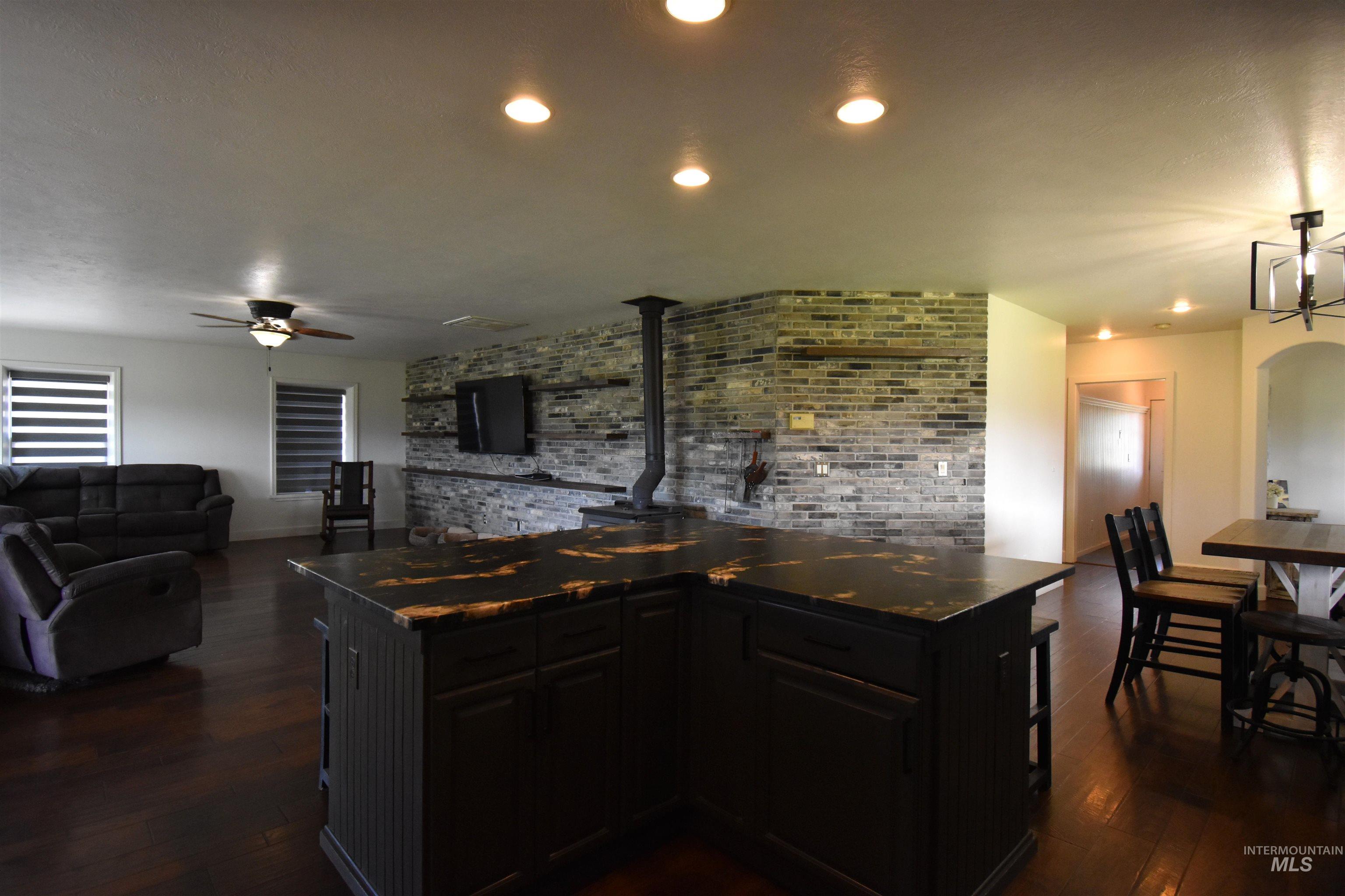 2599 Fruitvale Glendale Road Council, ID 83612 - Photo 17 of 29 Kitchen featuring dark cabinets, dark wood-style floors, a kitchen bar, brick wall, and dark countertops