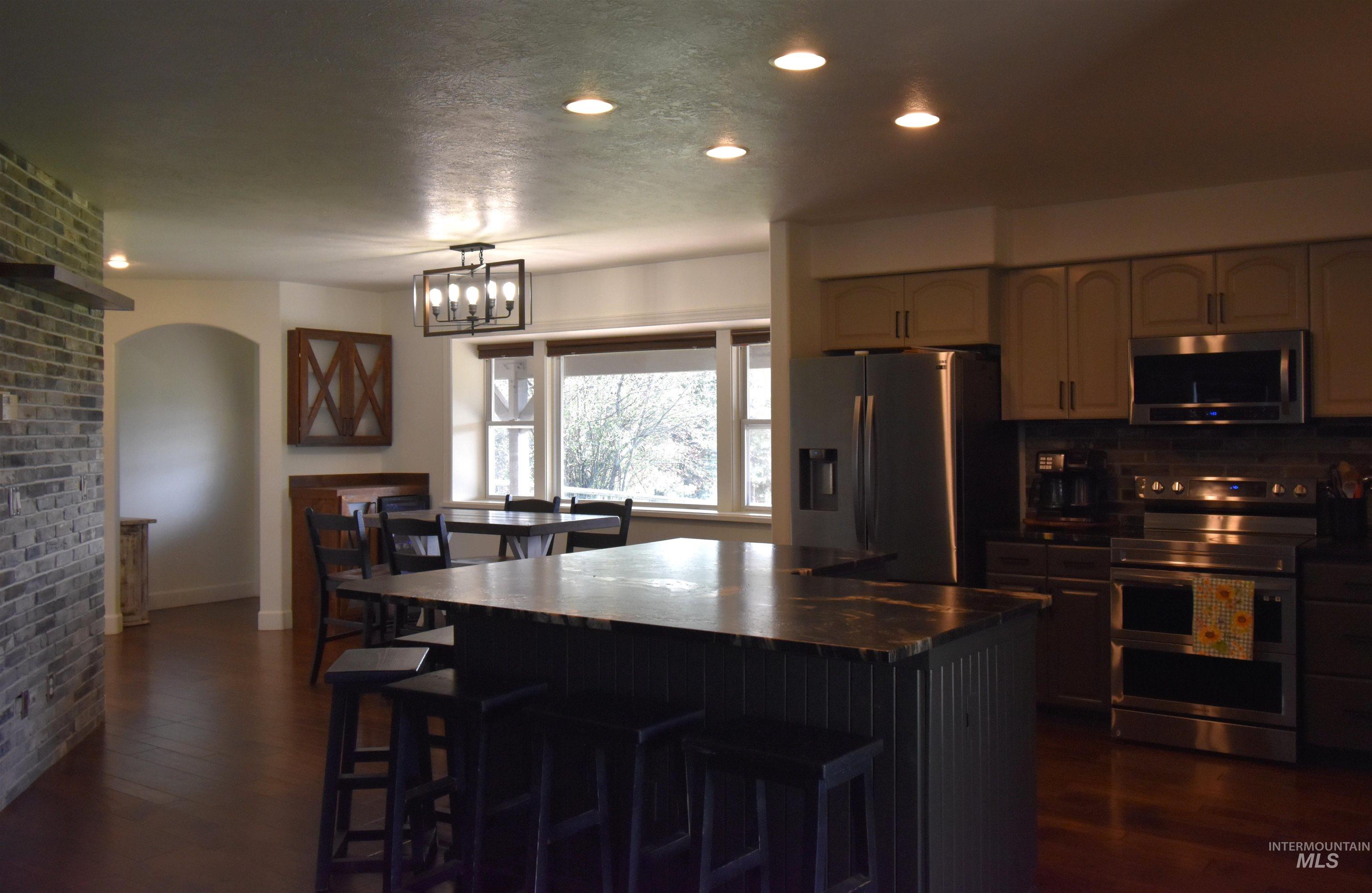 2599 Fruitvale Glendale Road Council, ID 83612 - Photo 19 of 29 Kitchen with stainless steel appliances, a center island, a breakfast bar, dark countertops, and dark wood-style flooring