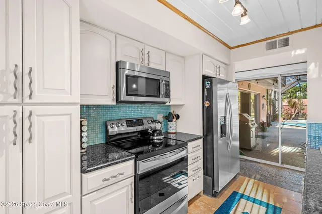 a kitchen with stainless steel appliances granite countertop a dining table chairs and a refrigerator