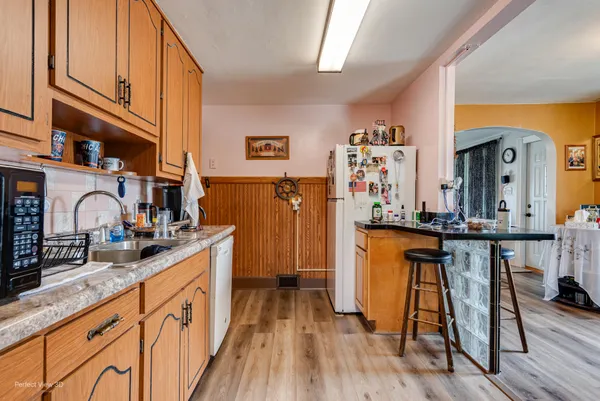 a kitchen with stainless steel appliances granite countertop a refrigerator a stove top oven and a dining table with wooden floor