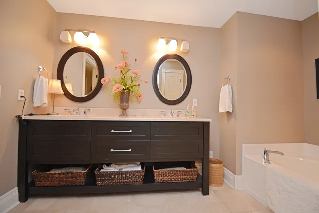 a bathroom with a double vanity sink a large mirror and a bathtub