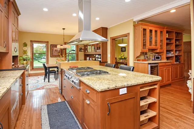 a kitchen with stainless steel appliances granite countertop table chairs sink and cabinets
