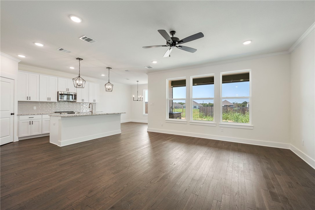 569 Harvest Lk Drive Snook, TX 77879 - Photo 3 of 22 Unfurnished living room featuring ornamental molding, dark wood-type flooring, a chandelier, a ceiling fan, and recessed lighting