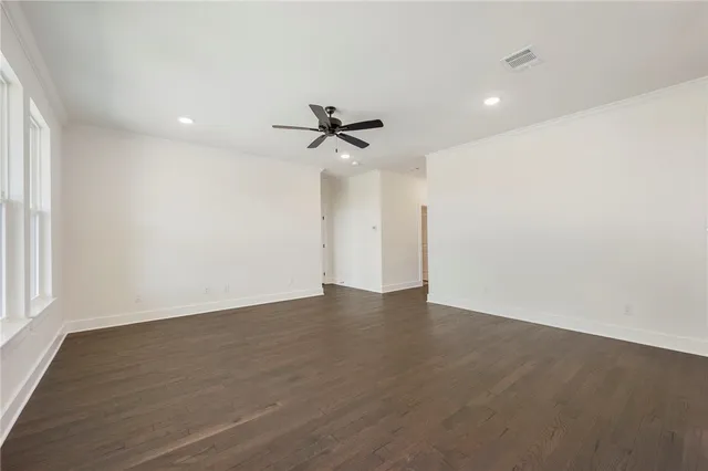 an empty room with wooden floor and ceiling fan