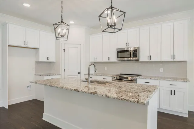 a kitchen with stainless steel appliances granite countertop a sink a stove and a white cabinets
