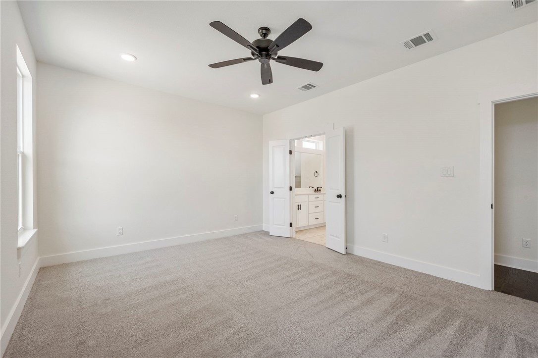 569 Harvest Lk Drive Snook, TX 77879 - Photo 9 of 22 Unfurnished bedroom featuring light colored carpet, ceiling fan, recessed lighting, and ensuite bath