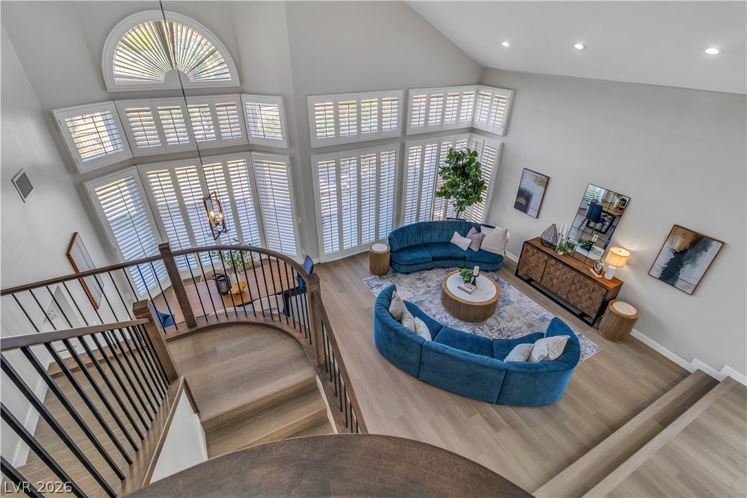 8848 Rainbow Ridge Drive Las Vegas, NV 89117 - Photo 19 of 43 A grand, naturally illuminated living space features towering ceilings, warm wooden floors, and a graceful curved staircase.